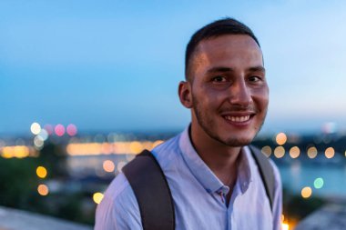 Sırt çantası ile genç yakışıklı adam bir gün batımı sırasında nehirde zevk