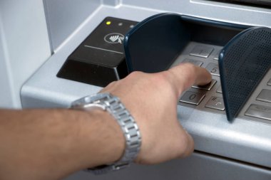 ATM makinesi ve yakın plan adam pin tuşuna basıyor. ATM arama paneline kişisel kimlik numarası girildi 