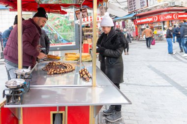 İstanbul, Türkiye - 12 Ocak. 2024: Şapkalı kadınlar sokakta mısır alıyor
