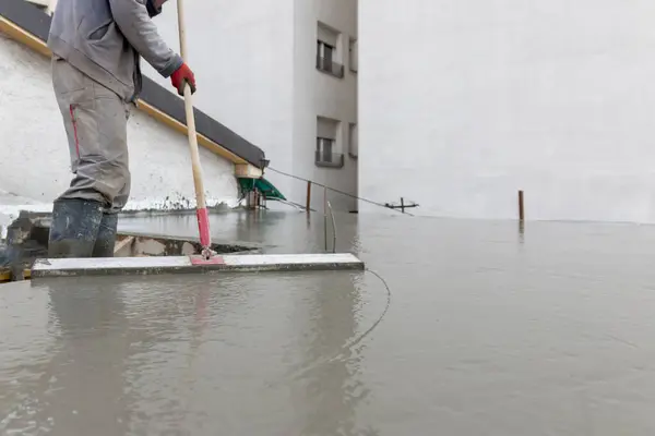 Beton döktükten sonra zemini düzleştirme işlemi. İnşaat alanında kare malayla beton plaka döşeyen bir işçi. İnşaat işi, kendin-yap, ev konsepti üzerinde hassas çalışma..