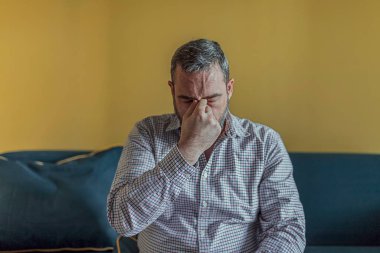 Sakallı İşadamı Duygu Yorgun Yorgun, Kronik İş Stres. Zor iş gününden sonra baş ağrısı çeken adam, evde kanepede oturuyor