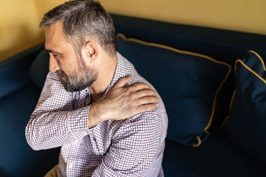 Evde boyun veya omuz ağrısı çeken mutsuz bir adam. Omuz ağrısı sağlık bakımı değil neden olur. İnsanlar, Sağlık Ve Sorun Kavramı.