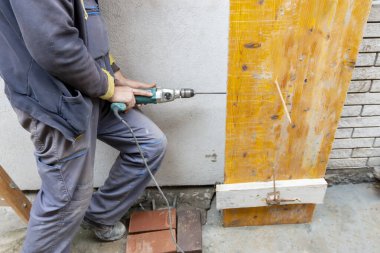 İşçi inşaat alanına beton dolgu için sütun formları kuruyor ve monte ediyor. Tahta sütun, çiviler kullanılarak ustalıkla güvence altına alındı. İnşaat teknolojileri.