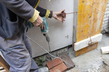 İşçi inşaat alanına beton dolgu için sütun formları kuruyor ve monte ediyor. Tahta sütun, çiviler kullanılarak ustalıkla güvence altına alındı. İnşaat teknolojileri.