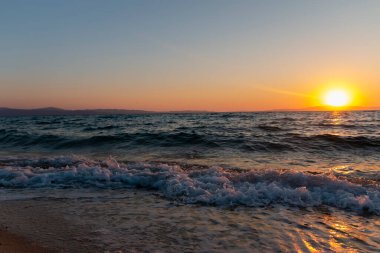 Sahildeki altın kumda deniz dalgaları. Günbatımlı ya da gün doğumlu güzel tropikal doğa deniz okyanusu