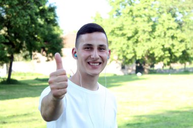 Müzik başparmak yukarıya genel parkta genç adamla portresi 