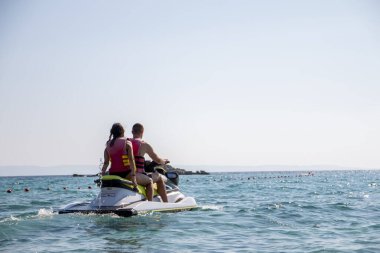 Çift jet ski sürüyor ve deniz manzarasının tadını çıkarıyor..