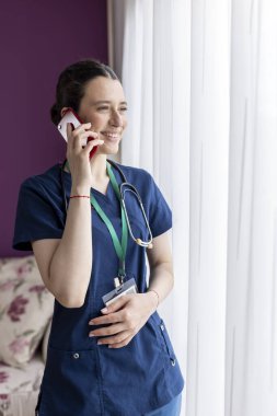 Genç bayan doktor telefonda konuşuyor ve gülümsüyor..
