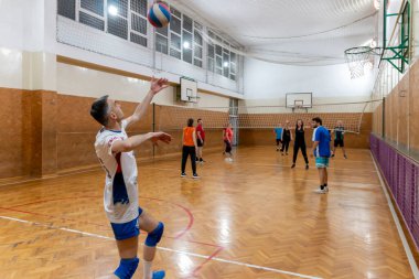 Olgun bir adam voleybolda topu servis ediyor. Voleybol oynayan arkadaşlar. Kapalı alandaki bir grup insanla spor maçı. Belgrad, Sırbistan - 10 Mayıs. 2024.