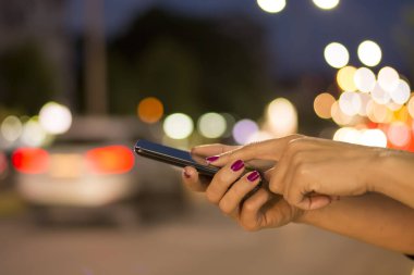 Işık gece ışıkları ile şehir Caddesi 'nde cep telefonu kullanan kadın görünümü