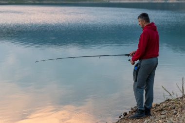 Genç adam gölde balık tutuyor..