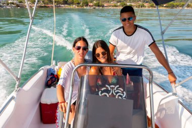 Üç arkadaş yelkenli teknede eğleniyor.