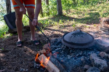 Şapkalı bir adam ızgarada barbekü yapmaya hazırlanıyor. Orman konseptinde yemek pişirmek.