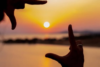 Gün batımında parmaklarıyla resmin şeklini oluşturan eller