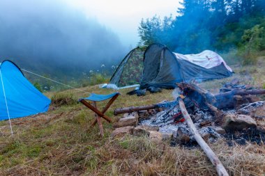 Dağlarda kamp yapmak. Sisli bir günde doğada çadır ve kamp ateşi.