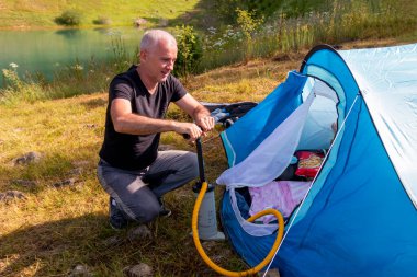 Son sınıf öğrencisi gün içinde çadırında bir şişme yatak şişiriyor..