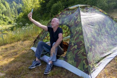 Çadırda kıdemli bir kampçı ormanda selfie çeker..