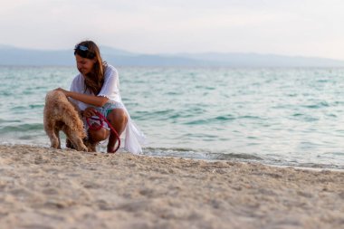 genç kadın köpeğiyle kumsalda oynarken