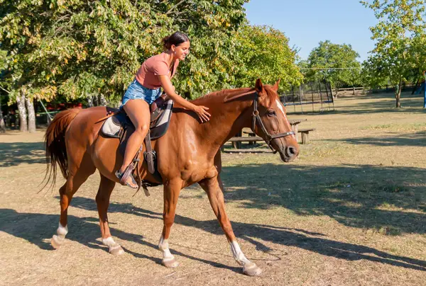 Genç, güzel, esmer bir kız ata binerken dörtnala koşuyor.. 