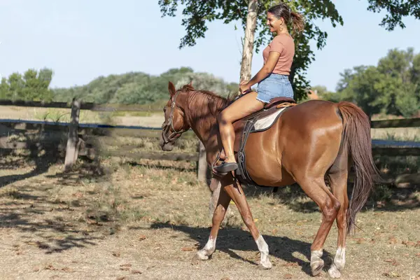 Çiftlikte ata binen bir kadın