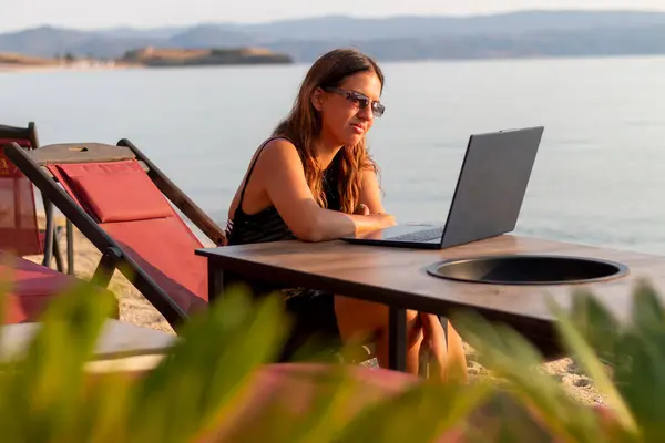 Bir kafede dizüstü bilgisayarla çalışan genç bir kadın. Serbest konsept.