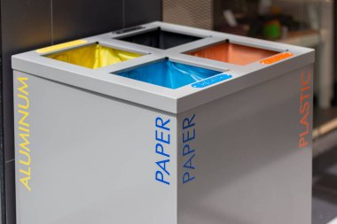 Atık ayıklamak için dört farklı çöp kutusu. Alüminyum için sarı, cam için siyah, kağıt için mavi. Çöplerin ayrıştırılması ve sıralanması, çevre kirliliği kavramı.