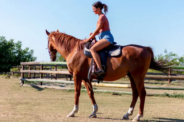 Takdire şayan kahverengi atına binen güzel bir kız çiftliğinde yarışa hazırlanıyor.