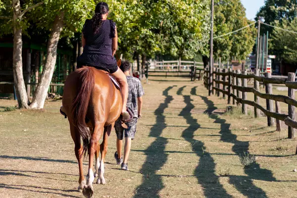 Eğitmen, kadının çiftlikte oturduğu ata liderlik eder..