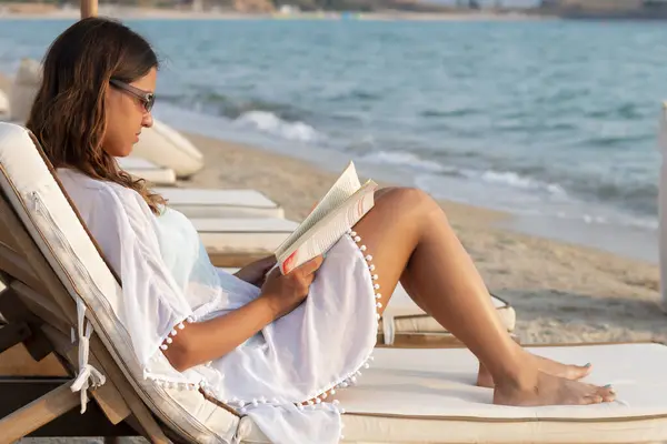 Kumsalda kitap okuyan güzel bir kadın.
