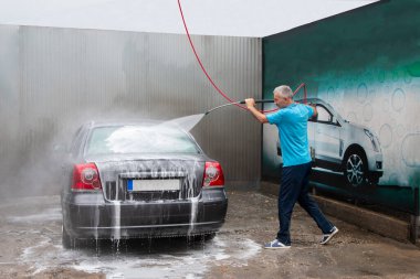 Araba yıkama. Olgun adam otomobili köpükle temizliyor. Araba oto yıkama servisi sırasında köpük şampuanıyla kaplı.