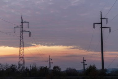 High voltage power lines at sunset. In future - scarcity of electricity. Due to high prices desperate people have no money to pay for electricity clipart