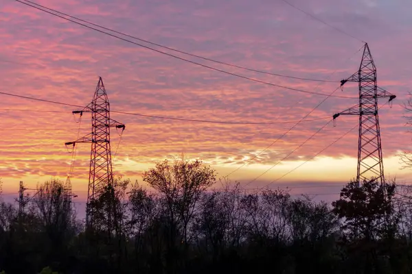 stock image High voltage power lines at sunset. In future - scarcity of electricity. Due to high prices desperate people have no money to pay for electricity