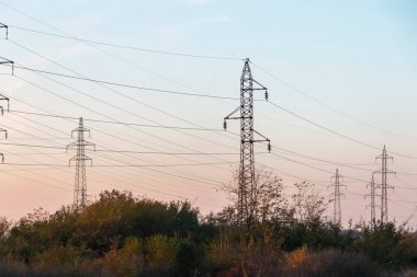 Gün batımında yüksek voltajlı elektrik hatları. Gelecekte elektrik sıkıntısı olacak. Yüksek fiyatlar yüzünden çaresiz insanların elektriğe verecek paraları yok.