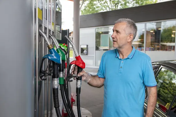 Olgun bir adam benzin deposuna benzin dolduruyor. Seyahat, ulaşım ve tatil