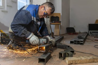 Mature man working with a circular grinder on a metal with sparks flying out of them. Metal works clipart