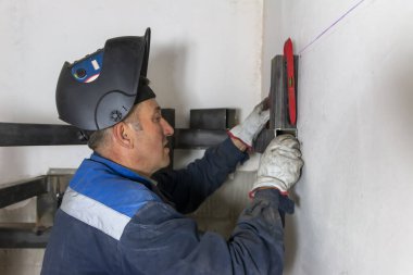 Tecrübeli bir adam ruh seviyesini kullanıyor ve bir inşaat alanındaki sarmal merdivenlere dikiş atıyor..