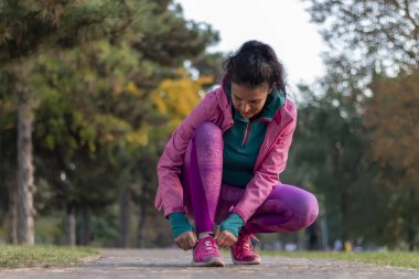 Forest Park 'ta sonbahar koşusu için bağcıklarını bağlayan koşucu kadın. Konsept - sağlık ve uygunluk