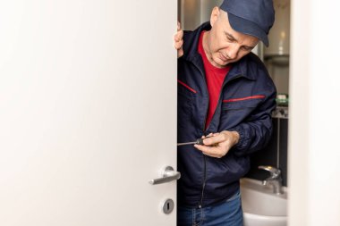 Olgun erkek marangoz iç kapı kilidi kurulumunda çalışıyor.