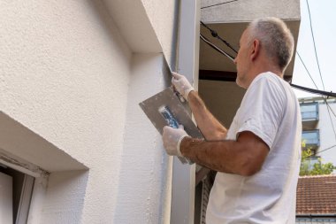 İnşaat işçisi son dekoratif cephe sıva macununu uyguluyor. Ev tadilatı. Apartman geliştirme ya da restorasyon işleri.