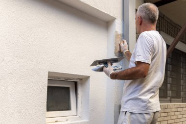 İnşaat işçisi son dekoratif cephe sıva macununu uyguluyor. Ev tadilatı. Apartman geliştirme ya da restorasyon işleri.