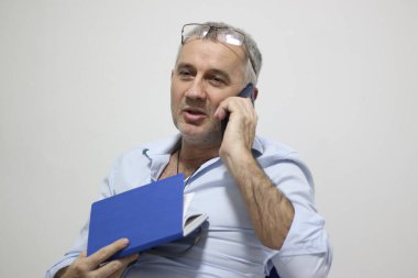 İyi çalışma gününün tadını çıkarıyorum. Ofisinde çalışırken cep telefonuyla konuşan kendine güvenen bir işadamı.