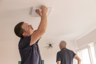 Concept installation of a ceiling led light. Hands of an electrician are installing and connecting a lamp to a ceiling. . Restoration in closed space. clipart