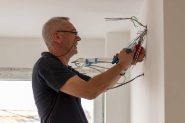 Elektrikçi, elektrik hattındaki kablo bağlantısını inceliyor. Teknisyen inşaat alanındaki kabloyu çekiyor. İnşaatçı, bağlantı kablolarını inceliyor..