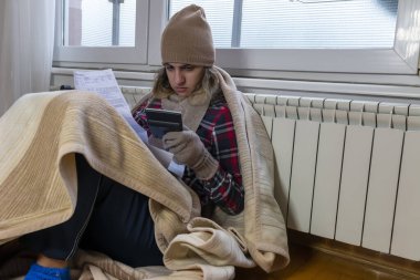 Isıtma faturasını okuyan endişeli genç bir kadın. Şaşırmış ve şaşırmış durumda: yüksek fatura faturası, borç bildirimi, kötü mali rapor, para sorunu