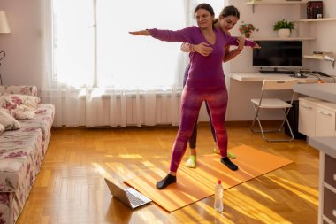 Kız, annesine egzersizin nasıl yapılacağını açıklar. Güzel bir iş kadını evde spor yapıyor, dizüstü bilgisayarda özel ders izliyor. İçerde nasıl formda kalınır