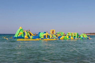 Su parkında çocuklar için yüzen şişme şişme şato. Deniz manzaralı su parkı.