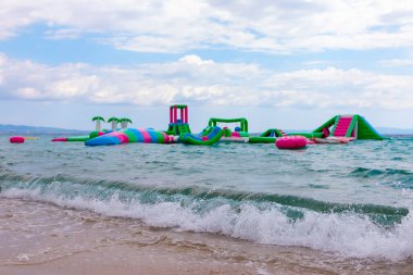 Şişme şişme şato suda yüzüyor. Su parkında eğlenen çocuklar için su parkı. Aquapark 'ın denizdeki cazibesi. Popüler turizm aktiviteleri, su sporları