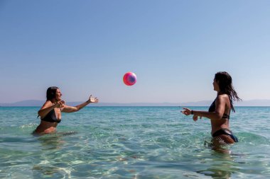 Yaz tatili, spor ve insan konsepti - genç mutlu insanlar plajda voleybol oynayıp eğleniyorlar.