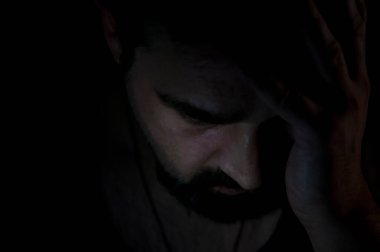 Karanlık odada sakal olan depresif adam. Sorunlar, anksiyete, üzüntü kavramı.