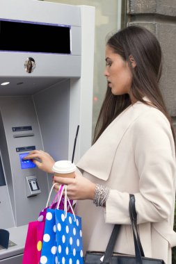 Alışveriş torbaları ile kahve yenilenirken otomatik vezne makinesi kullanarak çekici uzun saçlı esmer